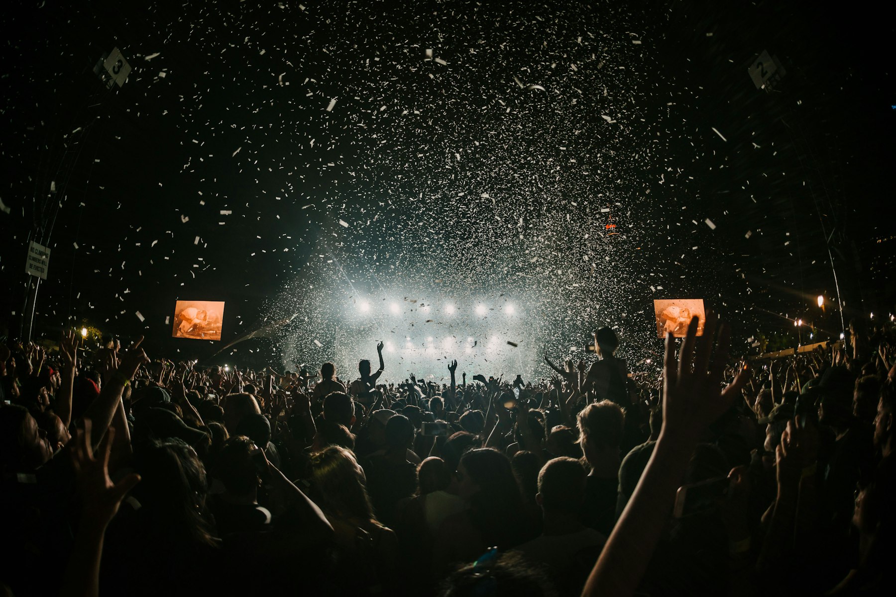 A crowd at a night concert under falling confetti